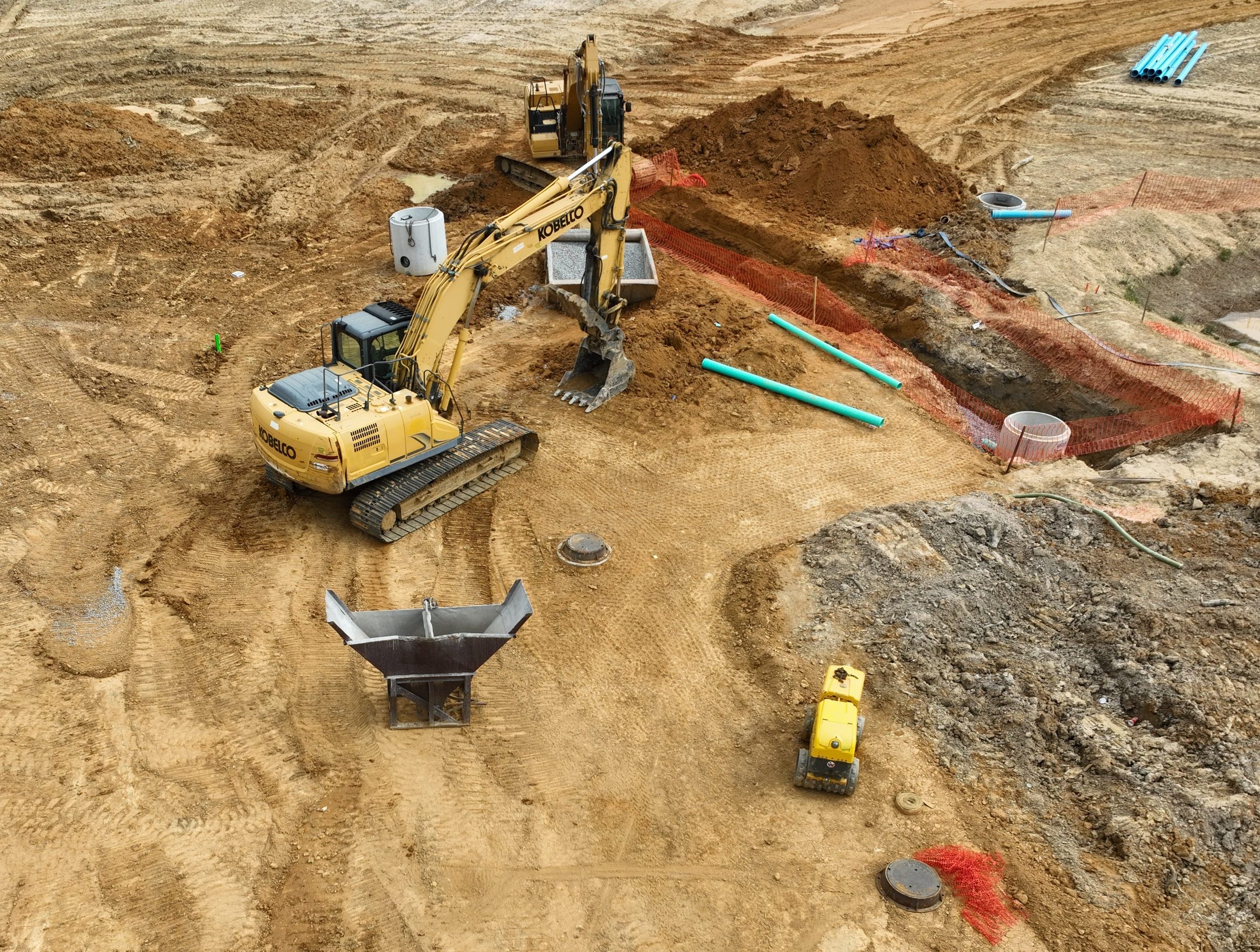 Overhead view of an excavator and roller installing storm pipe at Meadow Springs Run