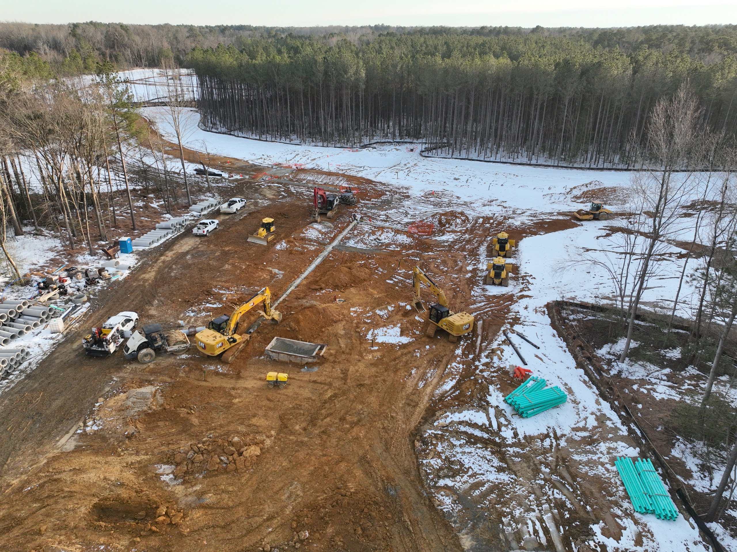 Aerial of the equipment fleet along a snow-covered utility corridor
