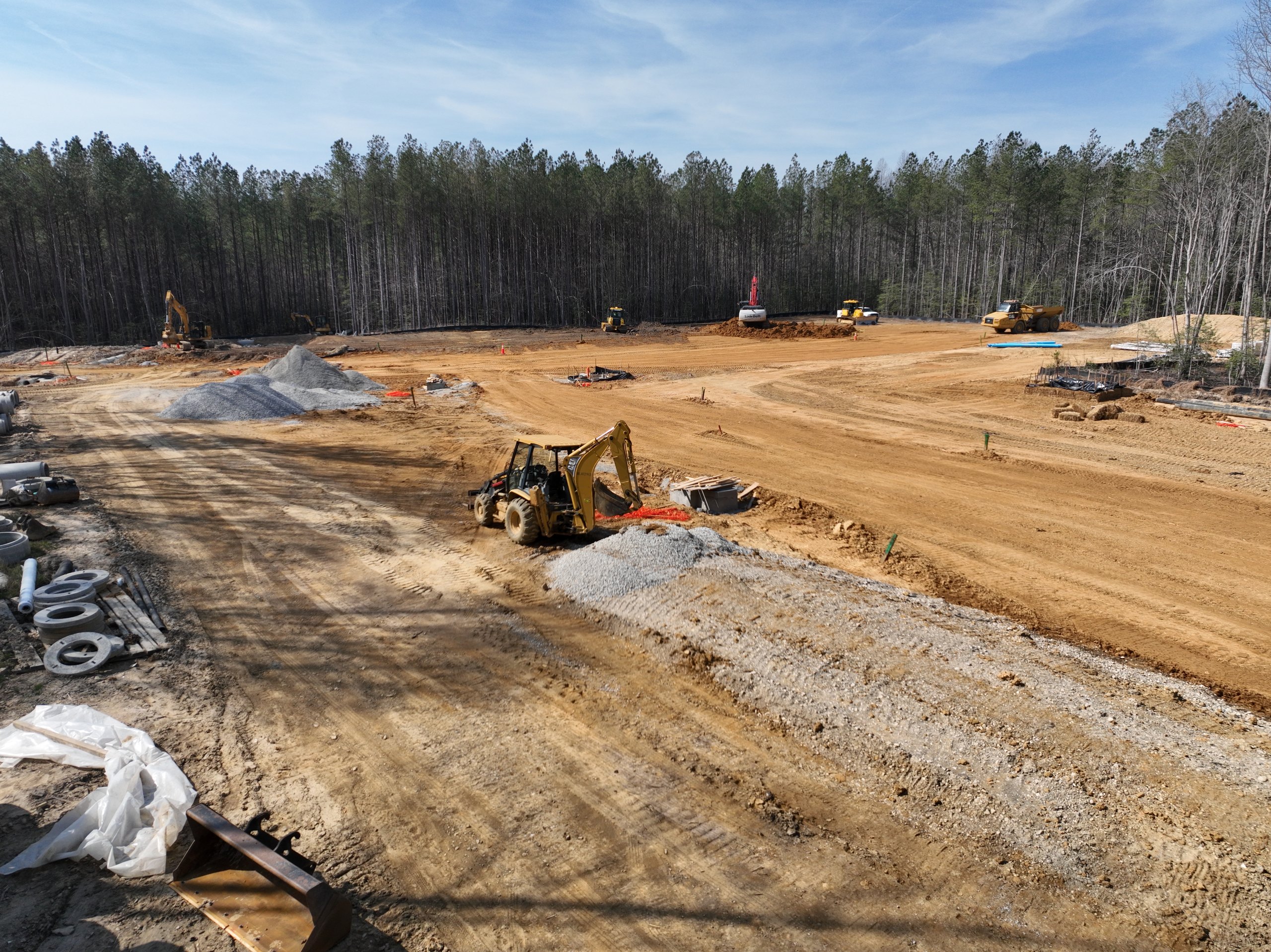 Ground-level view of the equipment fleet grading a broad site under an open sky