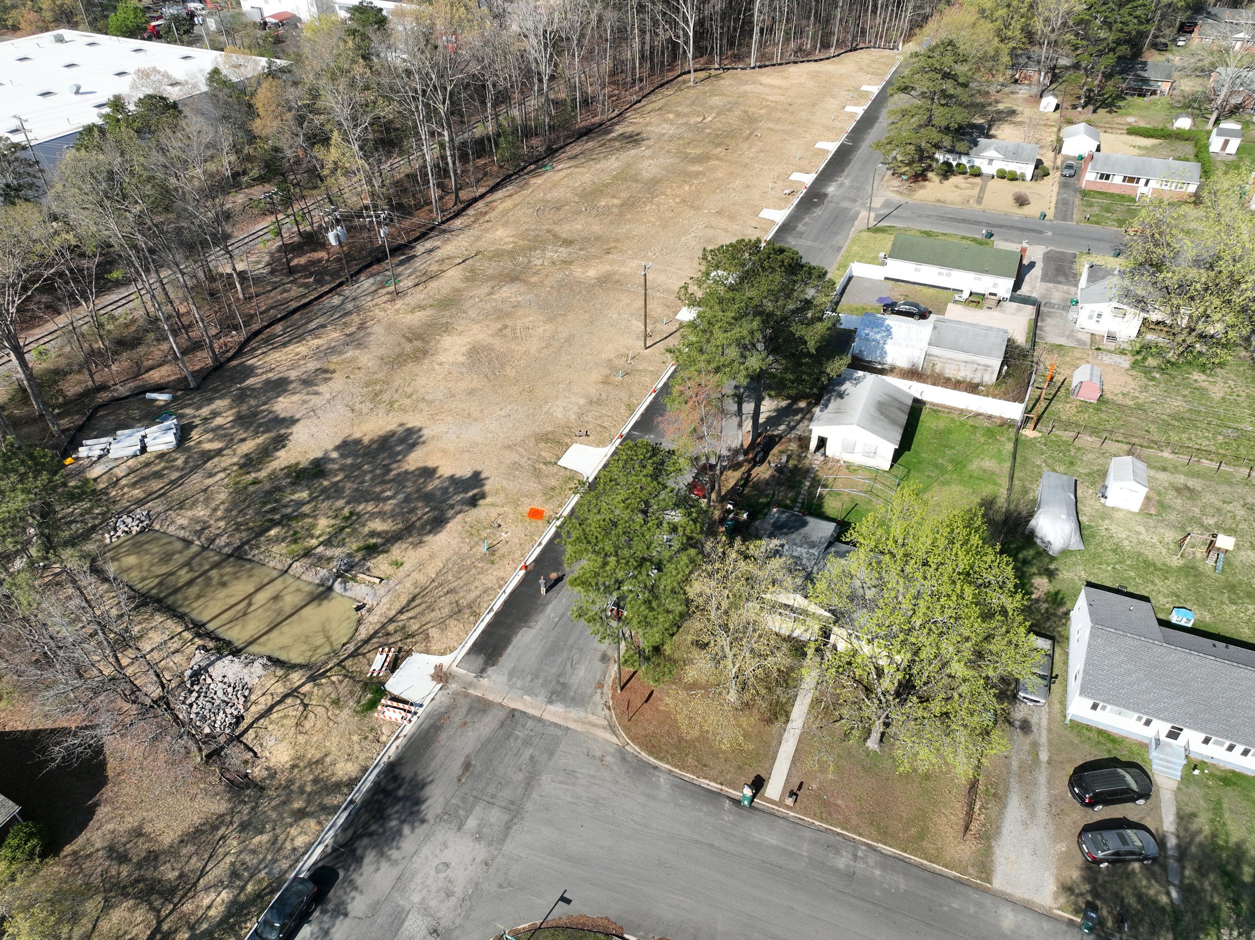 Aerial of finished York Manor lots: a new curbed street and graded homesites beside an established neighborhood