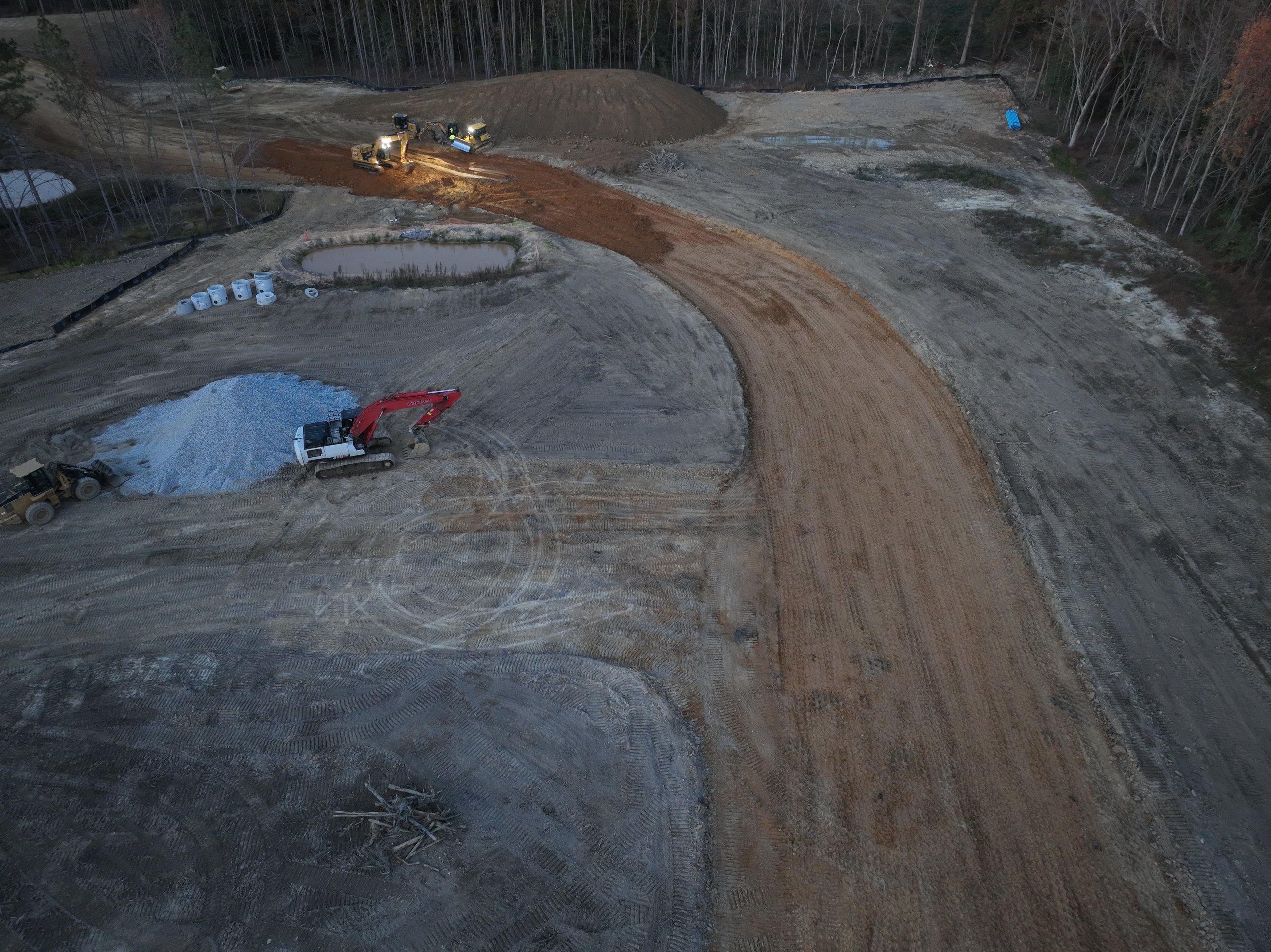 An excavator working a graded subdivision curve at dusk