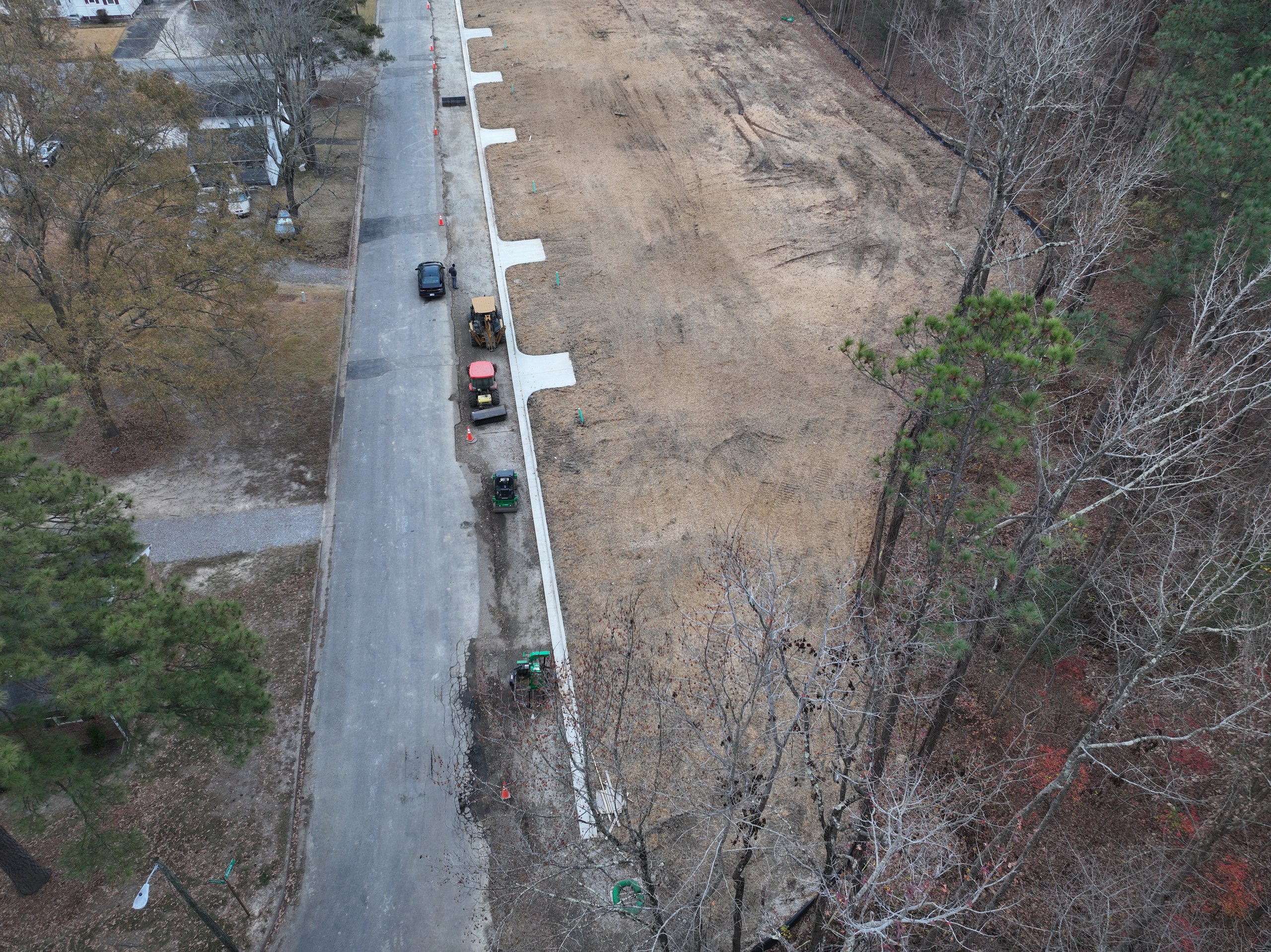 Aerial of finished lots with a paved street and curbs beside an established neighborhood