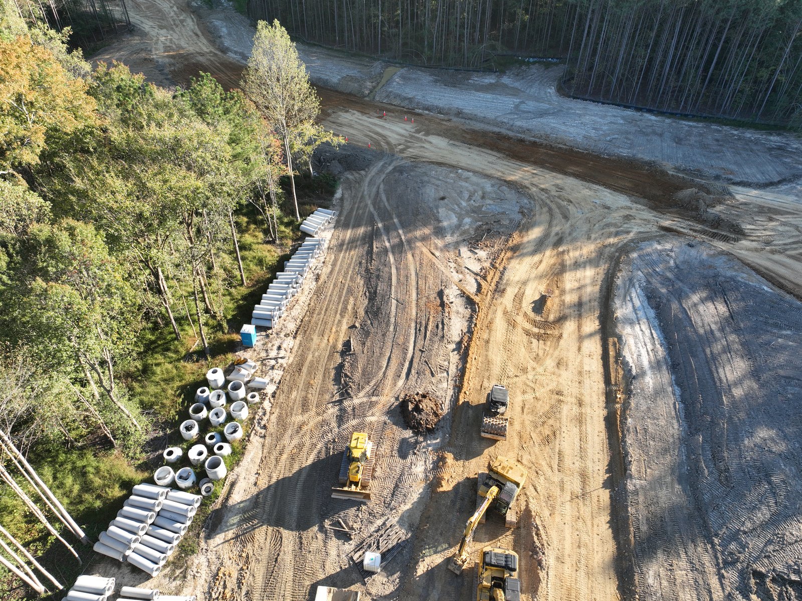 Aerial of two excavators working beside a stockpile of culvert pipe